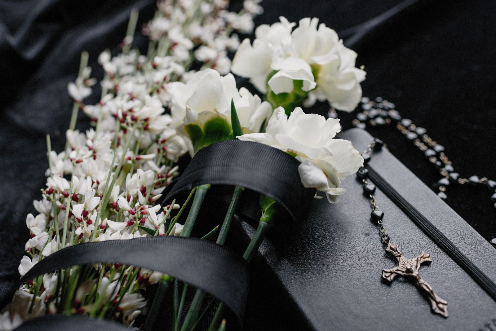 White memorial flowers resting on dark fabric