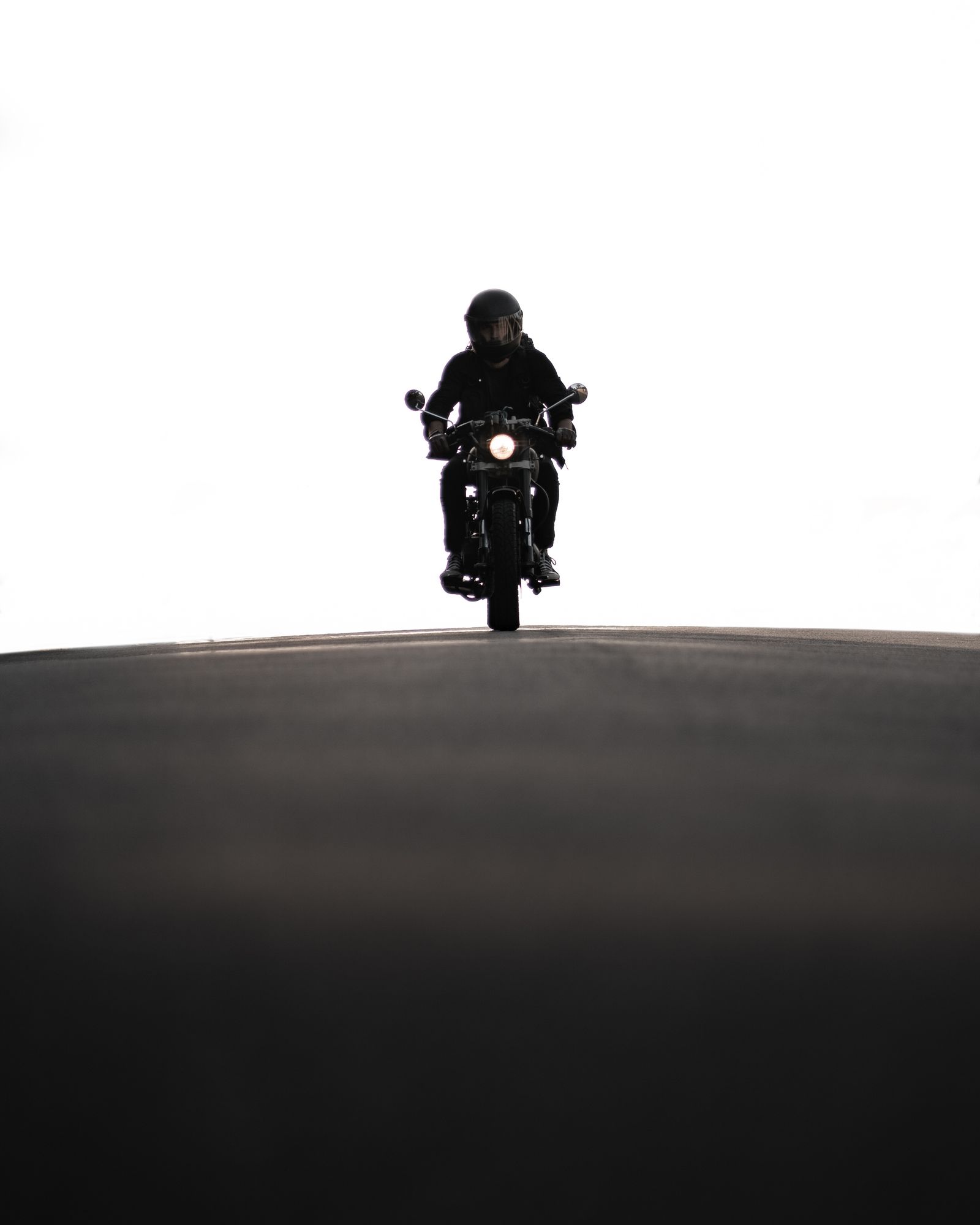 Helmeted motorcyclist riding a Los Angeles road at dusk